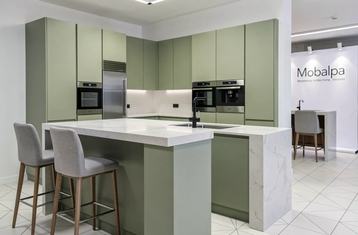 Cuisine Mobalpa Marseille avec façades vert sauge mat, îlot en quartz et électroménager intégré en acier inoxydable