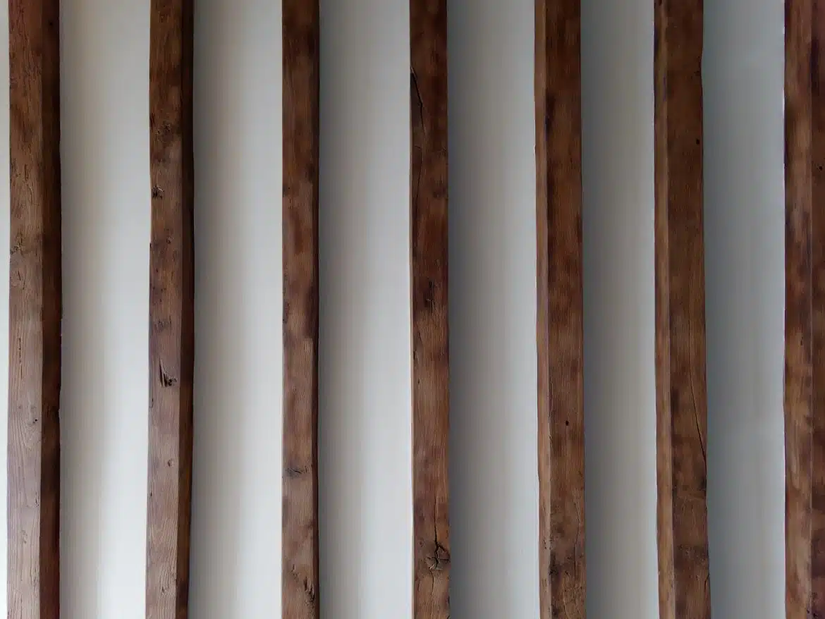 a row of wooden poles against a white wall